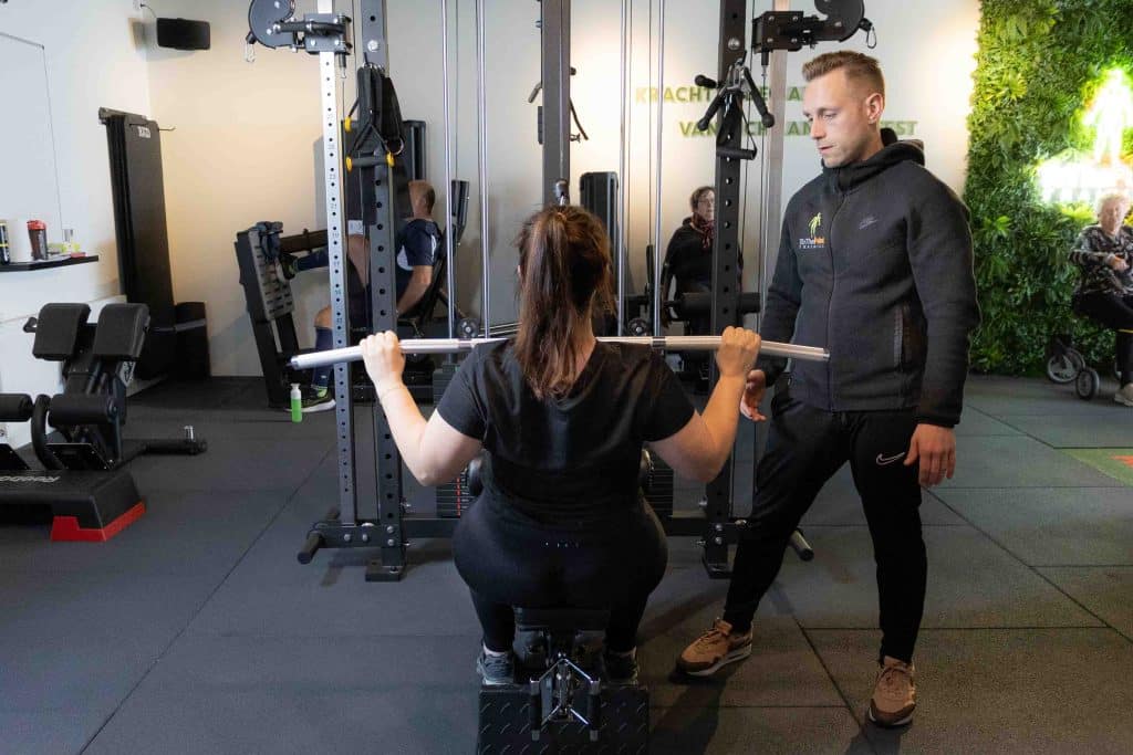 Personal trainer en osteopaat Frits Hitzel begeleidt een klant bij de uitvoering van een lat pulldown in de gym van ToThePoint Training.