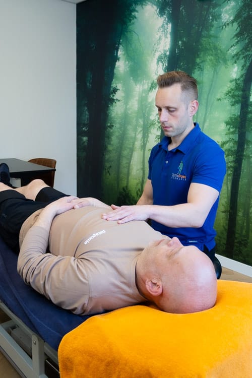 Osteopaat Frits Hitzel voert een osteopathische behandeling uit bij een volwassen cliënt in Tiel.