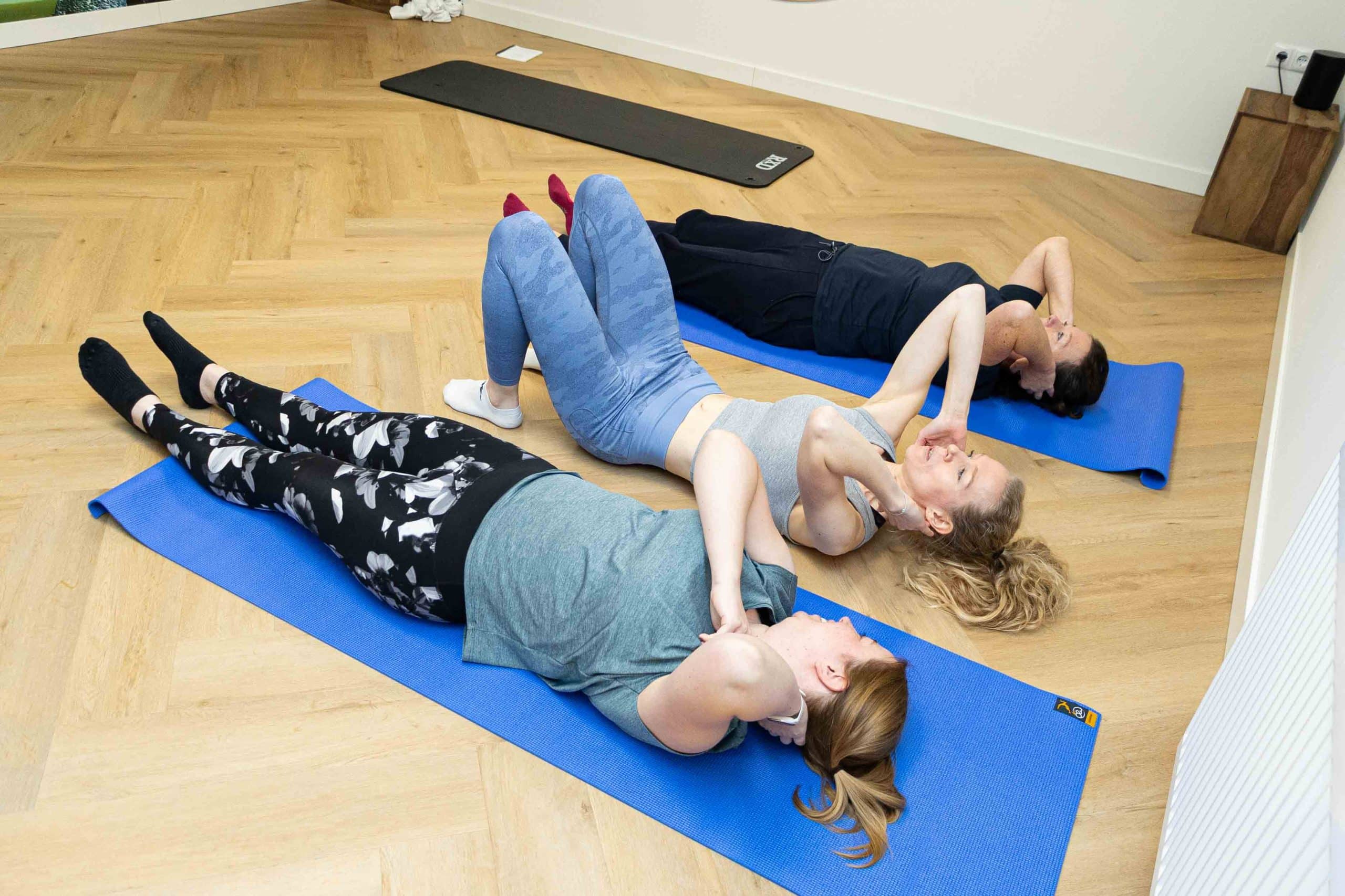 Pilatesgroep voert liggende oefeningen uit voor ontspanning en spierversterking.