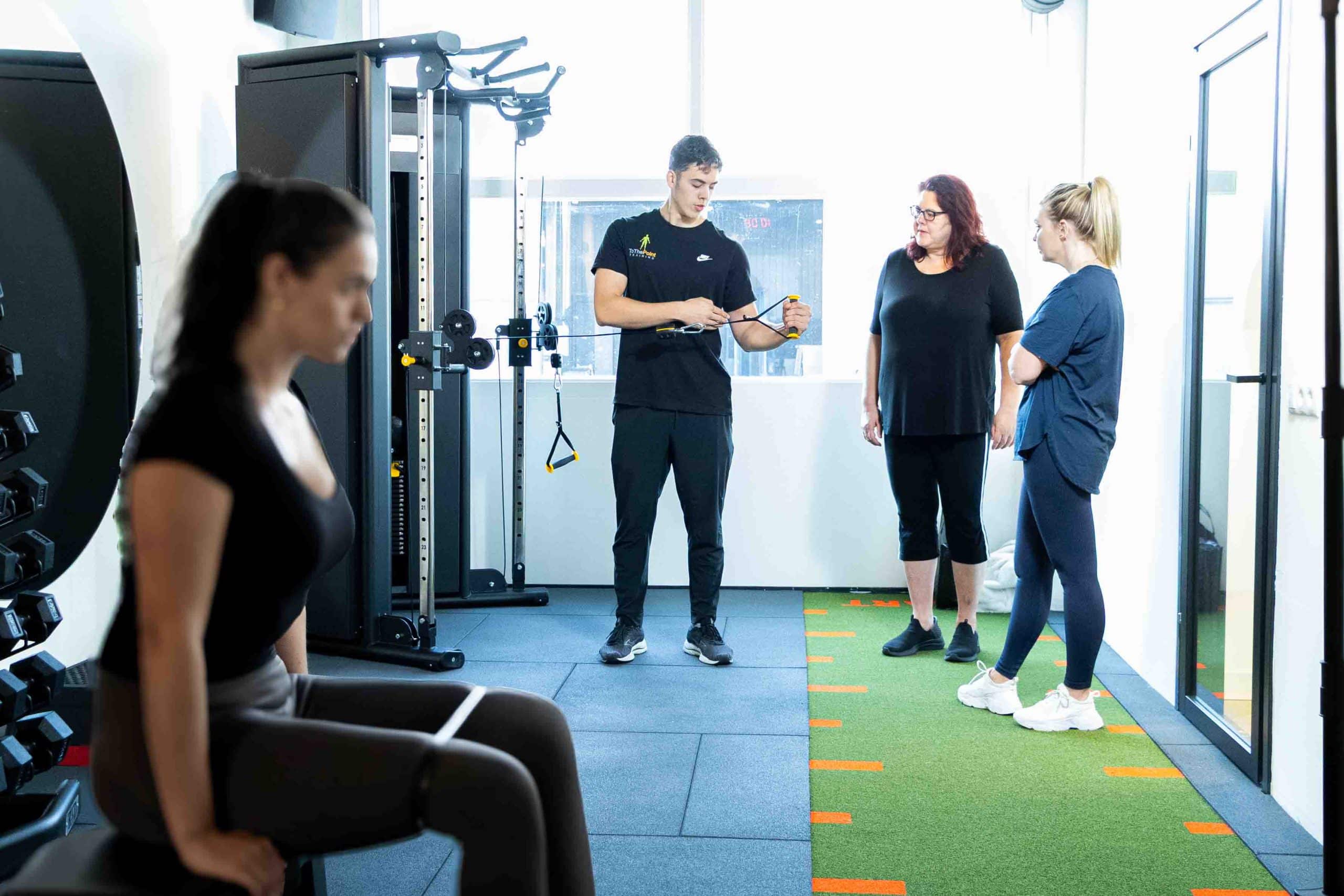 Personal trainer begeleidt duo training tijdens krachttraining om af te vallen